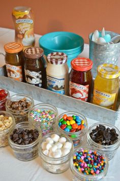 an assortment of desserts and confections are displayed in glass containers on a table