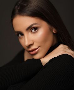 a woman is posing for a photo with her arm around her neck and wearing a black sweater