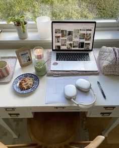 a laptop computer sitting on top of a desk next to a cup and saucer