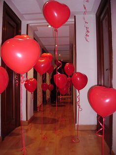 red balloons in the shape of hearts on a wooden floor