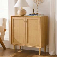 a wooden cabinet sitting next to a lamp on top of a hard wood floor near a window