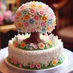 two tiered cake decorated with flowers and a tree on top