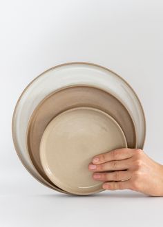 a person holding three plates in their hands on a white surface with one hand reaching for the plate