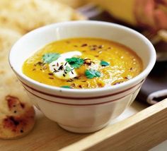 a white bowl filled with soup next to some pita bread on a tray,