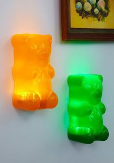 two gummy bears sitting next to each other near a framed painting on the wall