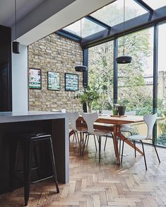 an open kitchen and dining room area with brick walls, hardwood flooring and large windows