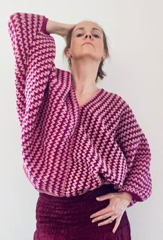 a woman in a purple and white sweater is holding her hands behind her head while looking up at the sky