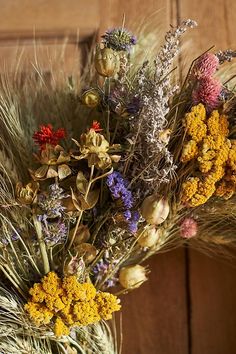 an arrangement of wildflowers and grasses in front of a wooden door