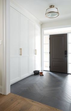 an empty room with white walls and wood flooring is pictured in this image, there are shoes on the floor next to the door