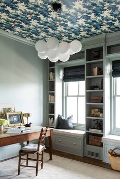 a home office with blue and white wallpaper on the ceiling