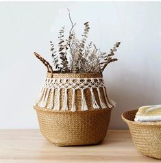 two woven baskets with plants in them sitting on a wooden table next to each other