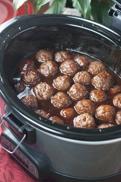 a crock pot filled with meatballs sitting on top of a red table cloth