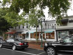 two cars are parked in front of a store on the side of the road near some trees