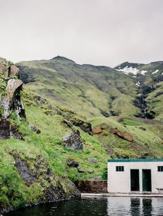 an outhouse on the side of a mountain next to a body of water