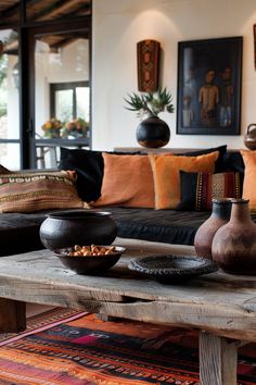 a living room filled with lots of furniture next to a wooden table topped with vases