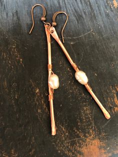 two pairs of copper and pearl earrings on a wooden table with wire wrapped around them