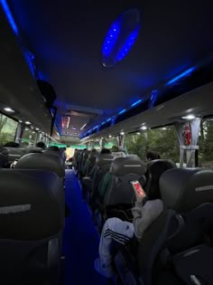 the inside of a bus with people sitting in seats and lights on it's ceiling