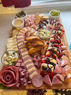 a wooden platter filled with different types of meats and cheeses on top of a table