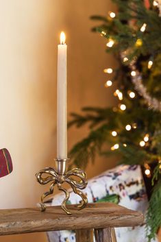 a lit candle sitting on top of a wooden table next to a christmas ornament