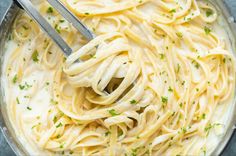 a bowl filled with pasta and topped with parmesan cheese, garnished with green herbs