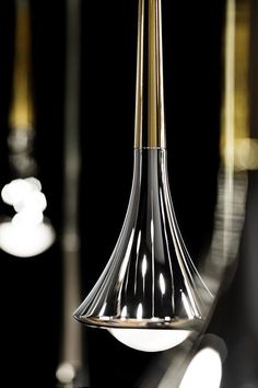 a black and gold colored lamp hanging from a ceiling fixture in a room with mirrors