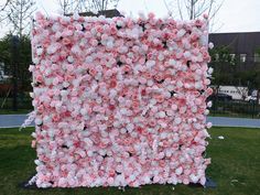 a large pink and white flowered wall in the grass