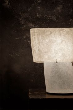 a light that is sitting on top of a wooden table next to a black wall