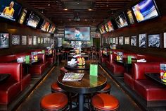 the inside of a sports bar with many televisions on the walls and tables in front of them