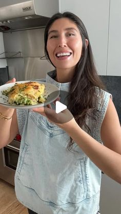 a woman holding a plate with food on it in her hand and smiling at the camera