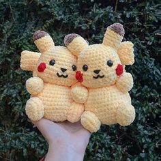 two crocheted pokemon stuffed animals are held up in front of some shrubbery