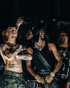 a group of men standing next to each other with tattoos on their arms and chest