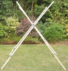 an outdoor sculpture in the middle of a grassy area with trees and bushes behind it