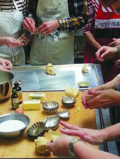 several people in aprons are preparing food on a table