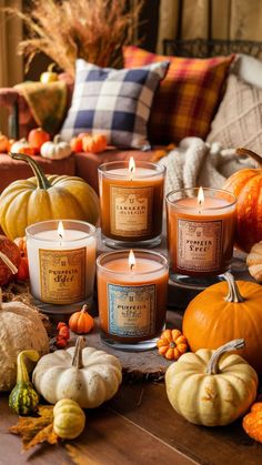 pumpkins, gourds and candles are arranged on a table with plaid pillows