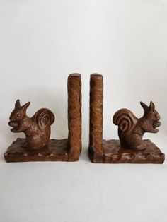 two brown squirrel bookends sitting next to each other on top of a white surface