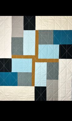 a quilted wall hanging with different colored blocks on it's sides and a cross in the middle