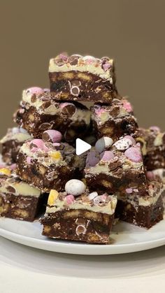 a white plate topped with lots of brownies covered in marshmallows and chocolate