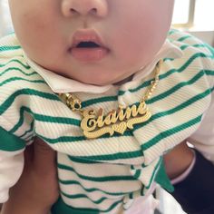 a close up of a baby wearing a name necklace