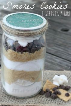 a jar filled with cookies and marshmallows on top of a wooden table