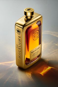 a bottle of whisky sitting on top of a table next to a glass container with a gold lid