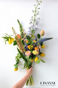 a person holding a bouquet of flowers against a white wall