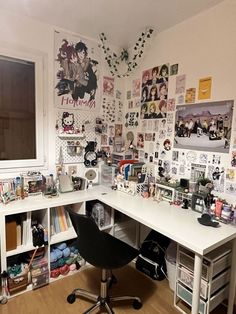 a desk with many pictures on the wall and a computer chair in front of it