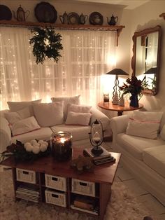 a living room filled with white furniture and christmas lights on the window sill,