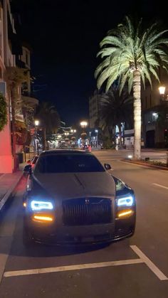 a car parked on the side of a street at night with palm trees in the background