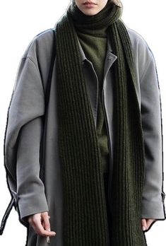 a woman wearing a green scarf and grey coat standing in front of a white background