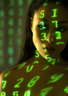 a woman with green numbers projected on her body in front of an array of numbers