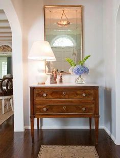 a wooden dresser sitting on top of a hard wood floor next to a white wall