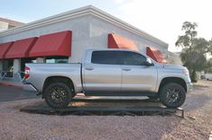 a silver truck is parked in front of a building with red awnings on it