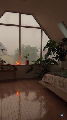 a bedroom with large windows and wooden flooring in front of the window is lit by candles