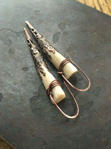 two silver and wood spoons sitting on top of a black stone slab next to each other